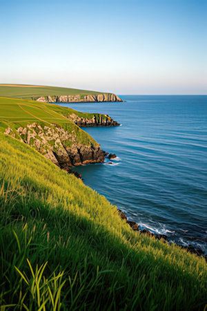 Beautiful seascape with green fields and blue sky at sunsetの素材