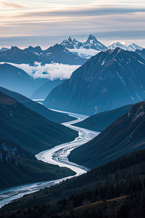 Mountain landscape with river and snow-capped peaks at sunsetの素材