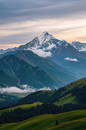 Beautiful alpine landscape with snowy peaks in the clouds at sunsetの素材