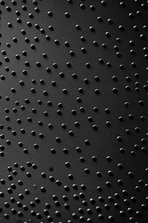 Black metal surface with small holes. Abstract background and texture for design.の素材