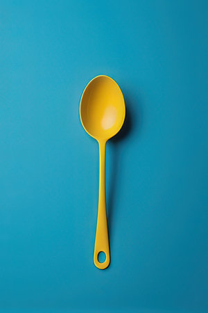Yellow plastic spoon on blue background. Flat lay, top view.の素材