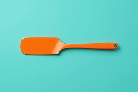 Orange plastic spatula on turquoise background. Minimal conceptの素材