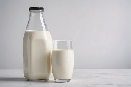 Bottle and glass of milk on white marble table against gray backgroundの写真素材