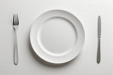Empty plate, knife and fork on white background. Top view.