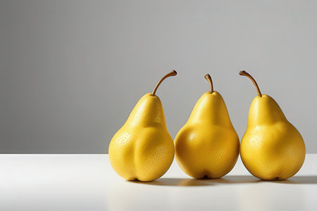 Three yellow pears on a white table and gray background with copy spaceの写真素材