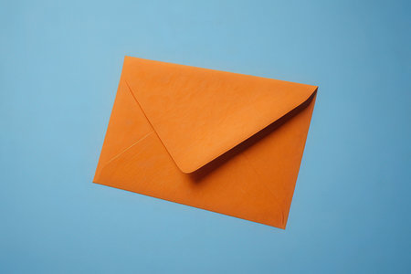 Orange envelope on blue background. Flat lay, top view, copy space.の写真素材