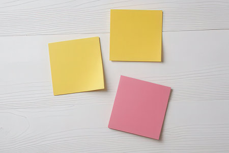 Yellow and pink sticky notes on a white wooden background. Top view