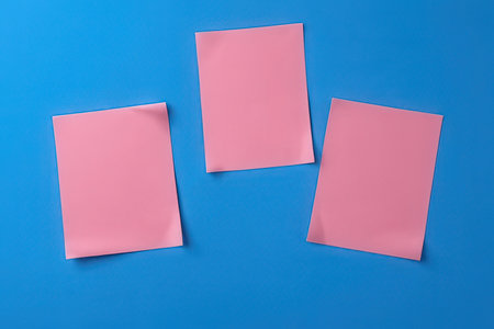 Three pink paper sheets on blue background. Mockup for design.の写真素材
