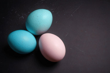 Three pastel colored easter eggs on a black background with copy spaceの写真素材