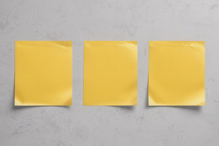Three yellow sticky notes on concrete background. Top view, copy spaceの写真素材