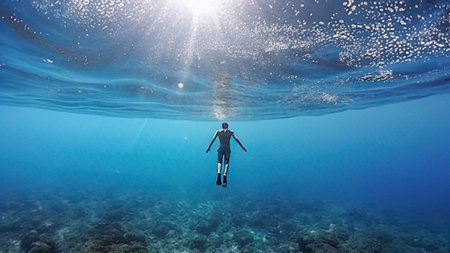 Underwater view of man with scuba diving mask swimming in sea.の写真素材