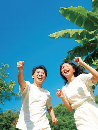 Happy asian young couple having fun in the park with blue skyの写真素材