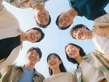 Group of asian people standing together in a circle with blue sky backgroundの写真素材