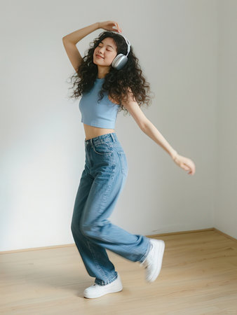 Young beautiful girl dancing and listening to music with headphones in the roomのeditorial素材