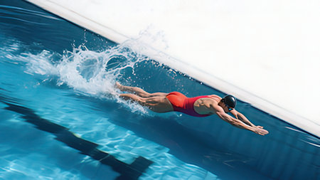 Young woman diving into swimming pool on a sunny day in summer.の写真素材