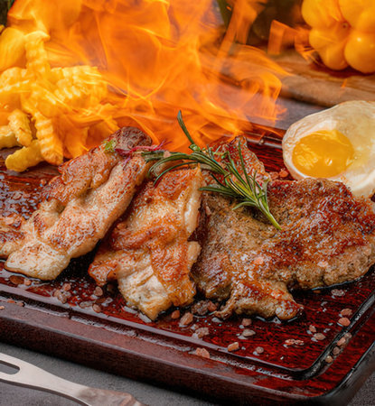 Pork chop on a wooden board with fried egg and vegetables.の写真素材