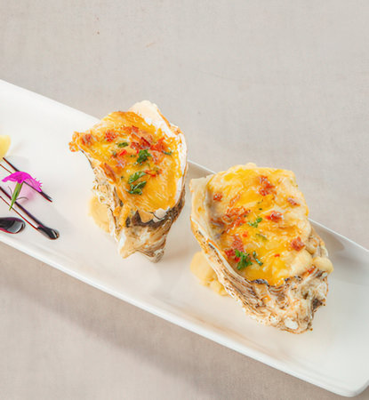 Baked oysters with cheese and herbs on a white plateの写真素材