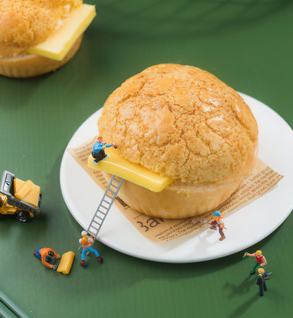 miniature workers with cheese buns on a green background.