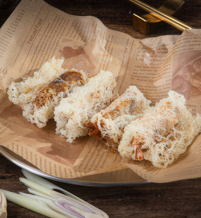 Fried spring rolls on wooden plate with chopsticks and napkin