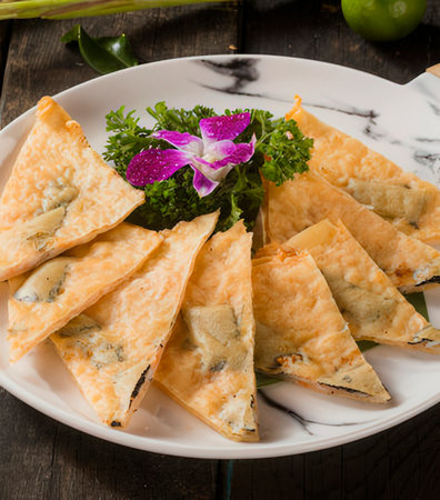 Crispy fried puff pastry with blue cheese and herbs on plateの写真素材