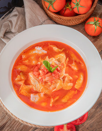 Cabbage soup with shrimps and tomatoes on a wooden table