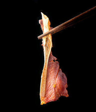 Raw meat with chopsticks isolated on black background.