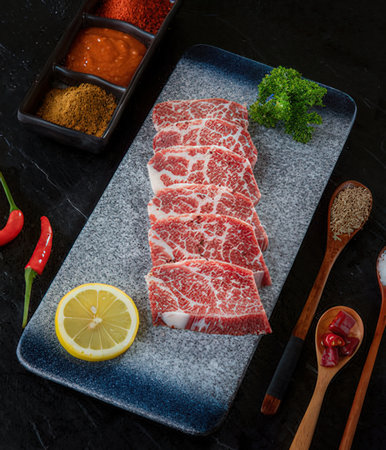 Sliced raw wagyu beef meat on black stone background