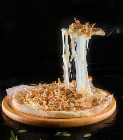 Pizza with salted caramel on a wooden plate on a black backgroundの写真素材