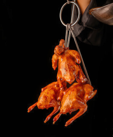 Fried chicken on a black background in the hands of a cookの写真素材
