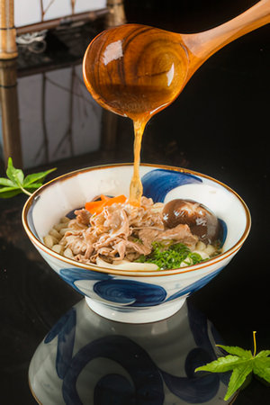 Rice noodles with beef and vegetables in a bowl with wooden spoon