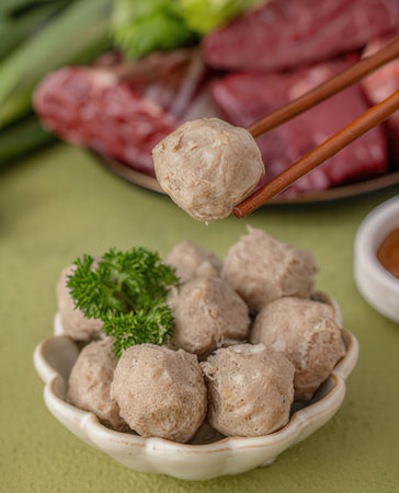 Meat ball dumplings in bowl with chopsticks on green backgroundの写真素材