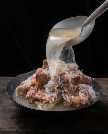 Pouring milk into a bowl of rice with pork on black backgroundの写真素材