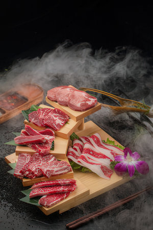 Beef sirloin on wooden plate with smoke on black backgroundの写真素材