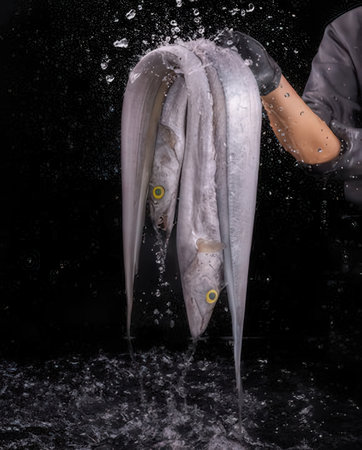Close-up of the hands of a woman who pours water on the fishの写真素材
