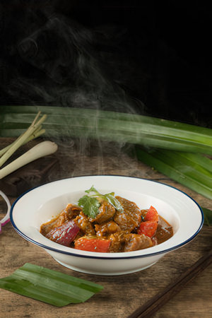 beef with red curry sauce in white bowl on black backgroundの写真素材