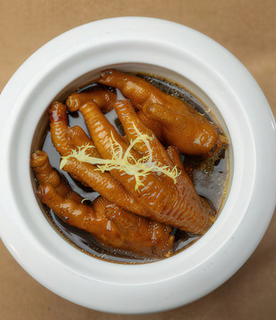 boiled chicken feet in a white pot on a brown background.の写真素材