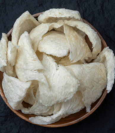 Bowl of raw coconut chips (close-up shot) on dark backgroundの写真素材
