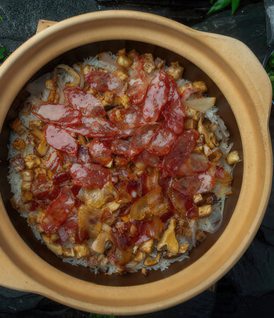 Crispy pork with rice in clay pot on black background.の写真素材