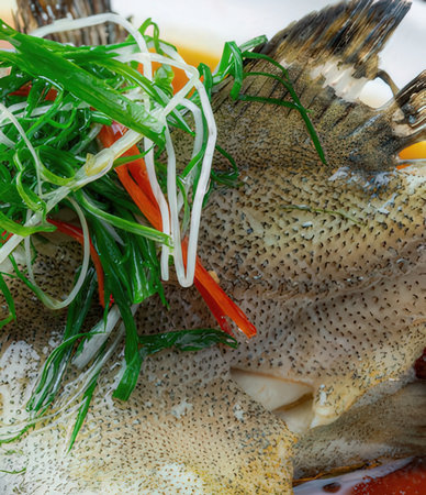 Fresh fish with vegetables on white background. Close up.