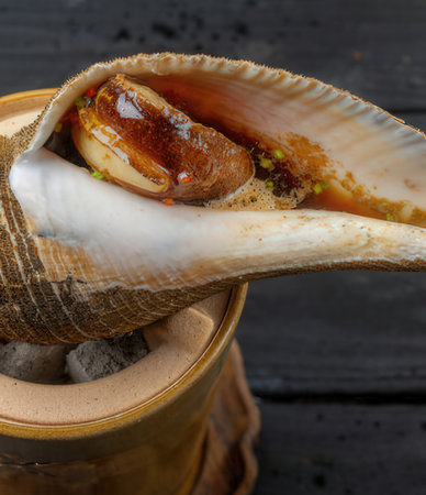 Delicious scallops in a clay pot on a black wooden table