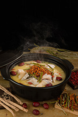 Chicken soup in a pot on a black background.