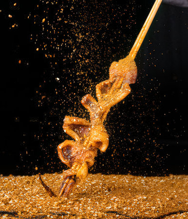 Fried squid on a black background with splashes of water.の写真素材