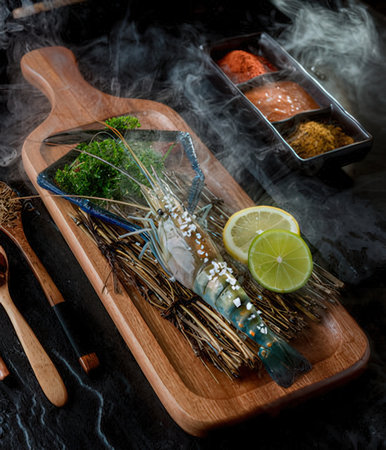Raw fresh shrimps on wooden cutting board with chopsticks and herbsの写真素材