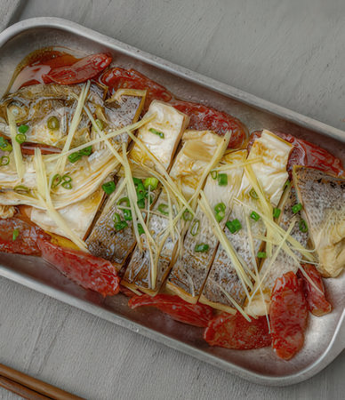 Seabass fish with spicy sauce and green onion on a tray