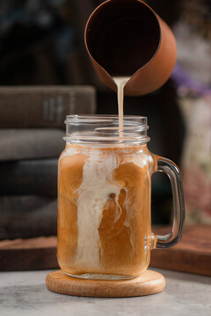Iced latte coffee in a glass jar on wooden table.の写真素材