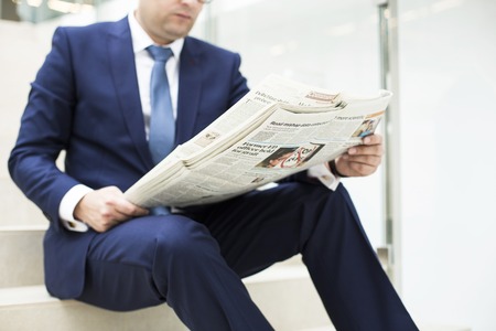 Portrait of a young handsome businessman reading a newspaperの写真素材