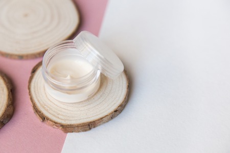 Beauty spa flatlay with cosmetic bottles, jar of face cream, succulent leaves and saw cut wood. Top...