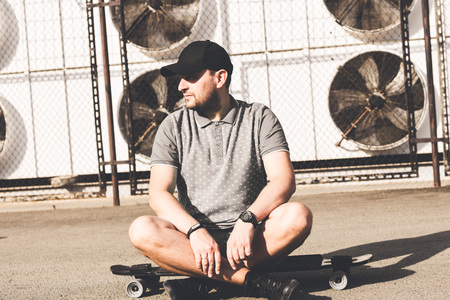 young man in a black cap on a city industrial background