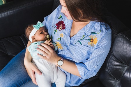 Happy multiethnic family sitting on the sofa in modern interiorの写真素材