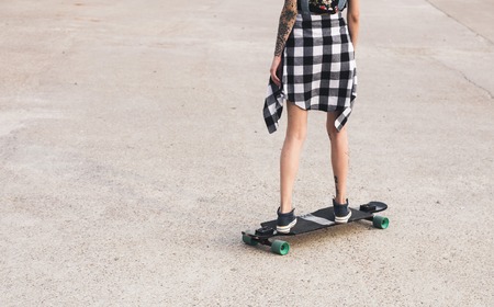 young girl with tattoo rides on a longboardの写真素材